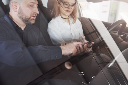 Assistant manager giving advices and help to the customer in automobile salon.