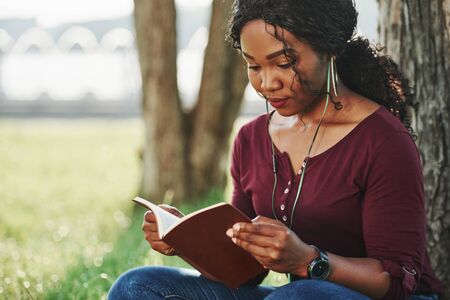 Concentrated look. Cheerful african american woman in the park at summertime.の写真素材