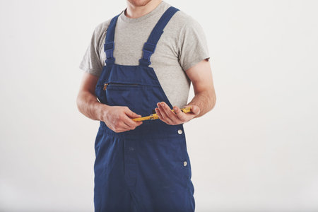 Headless view. Man in blue uniform stands against white background in the studio.