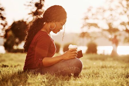 Almost sunset. Cheerful african american woman in the park at summertime.の写真素材