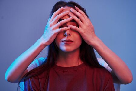 Sister covers eyes. Studio shot indoors with neon light. Photo of two beautiful twins.の写真素材