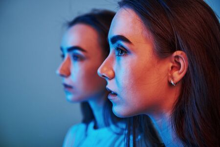 Focused photo. Studio shot indoors with neon light. Photo of two beautiful twins.の写真素材