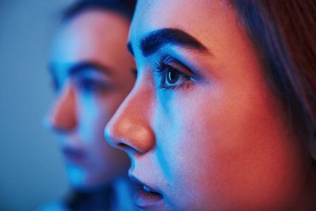 Futuristic conception. Studio shot indoors with neon light. Photo of two beautiful twins.