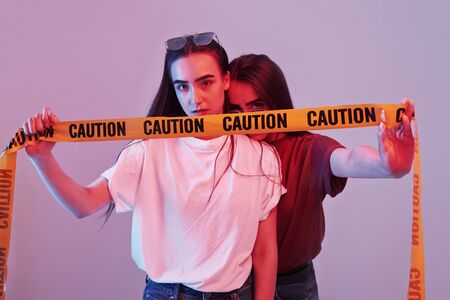 White and red shirts. Studio shot indoors with neon light. Photo of two beautiful twins.の写真素材