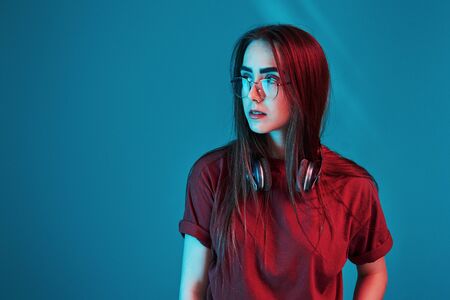 Illuminated by neon light. Studio shot indoors. Portrait of beautiful young girl.の写真素材