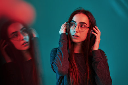 Nce reflection effect by using glass. Studio shot indoors with neon light. Portrait of beautiful...