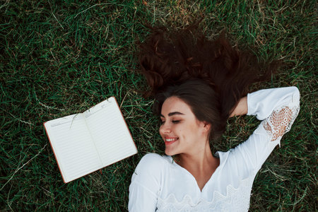 Top view. Girl lying down on the green grass and have a rest.
