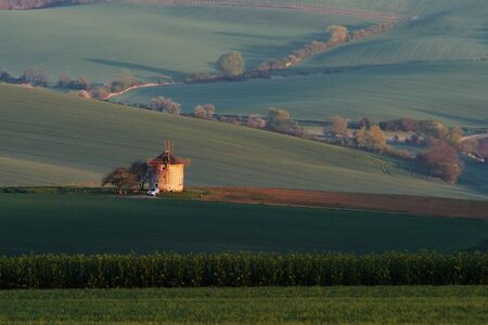 Majestic landscape of field in the evening. Windmill in the center of meadow.の写真素材