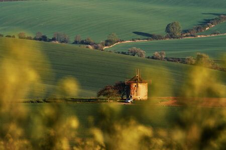 Majestic landscape of field in the evening. Windmill in the center of meadow.の写真素材