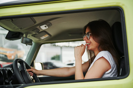 Pretty woman in the green modern car posing for the camera.