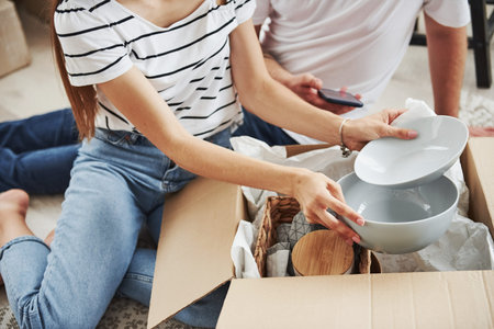 Particle view of couple in their new apartments unpacks their plates from boxes.