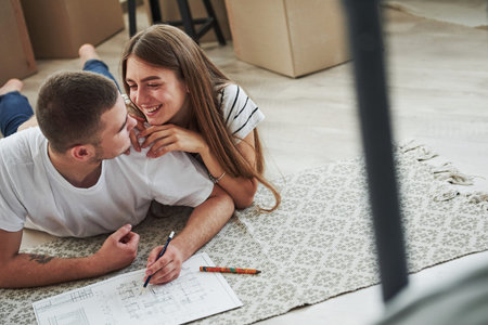 Filing document. Cheerful young couple in their new apartment. Conception of moving.の写真素材
