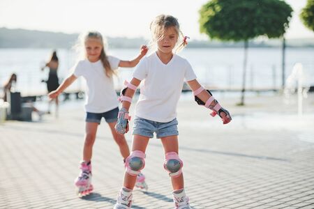 Two cute kids riding by roller skates in the park at daytime.の写真素材