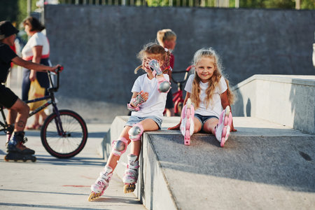 On the ramp for extreme sports. Two little girls with roller skates outdoors have fun.