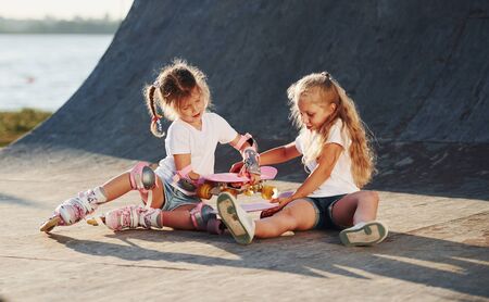 Trying new skate. Two cute female kids have fun outdoors in the park.の写真素材