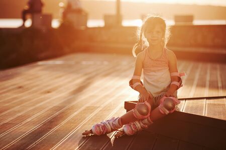 Happy cute kid with her roller skates. Unbelievable sunlight.の写真素材