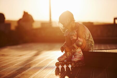 Happy cute kid with her roller skates. Unbelievable sunlight.の写真素材