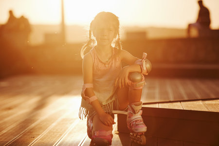 Happy cute kid with her roller skates. Unbelievable sunlight.の写真素材