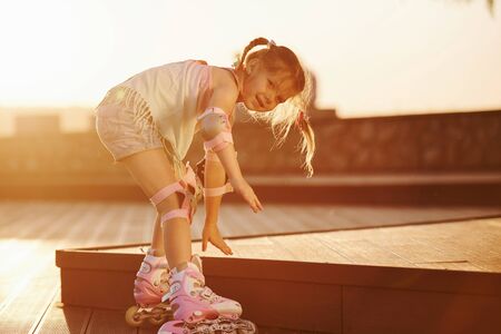 Happy cute kid riding on her roller skates. Unbelievable sunlight.の写真素材