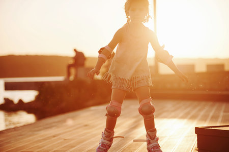 Happy cute kid riding on her roller skates. Unbelievable sunlight.