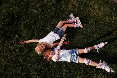 Top view. Feeling freedom. Two female kids lying on the green grass at summertime.