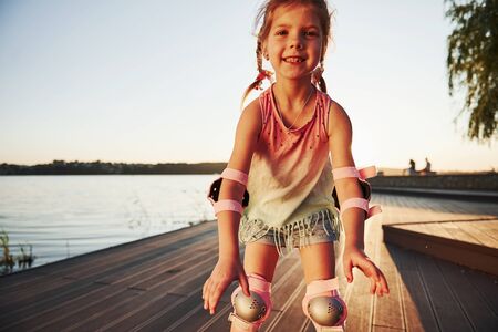 Happy cute kid riding on her roller skates. Summertime leisure and weekends.の写真素材