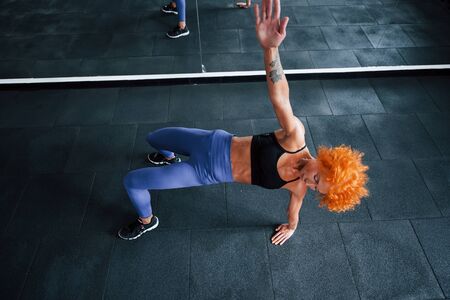 Top view. Sporty redhead girl have fitness day in gym at daytime. Muscular body type.の写真素材