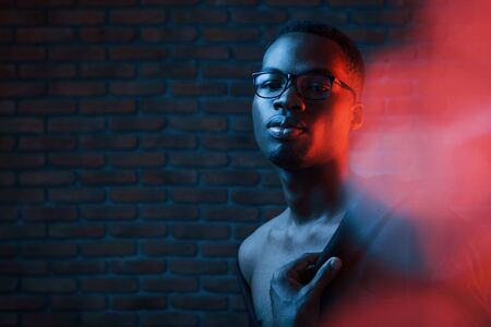 Light blinks. Futuristic neon. Young african american man in the studio.の写真素材
