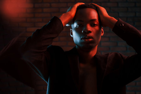 Beautiful reflection. Futuristic neon lighting. Young african american man in the studio.