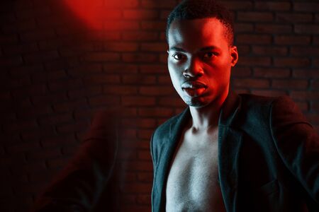 Beautiful reflection. Futuristic neon lighting. Young african american man in the studio.の写真素材