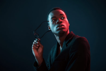 Fashion model. Futuristic neon lighting. Young african american man in the studio.