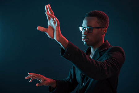 Hands in front. Futuristic neon lighting. Young african american man in the studio.