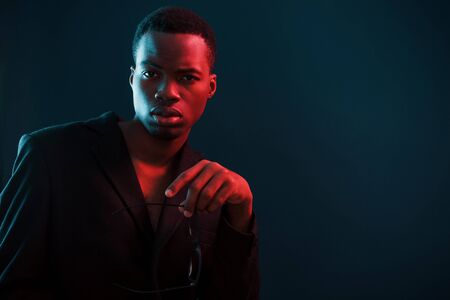 Fashion model. Futuristic neon lighting. Young african american man in the studio.の写真素材
