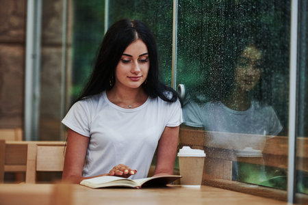 Portrait of young female student that sits in cafe at rainy day. One person only.の写真素材