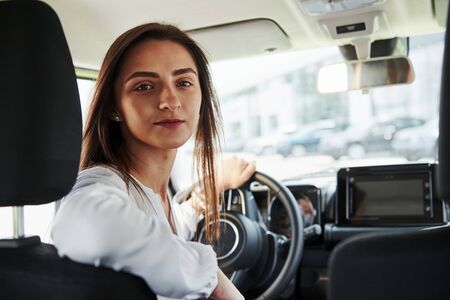 Cheerful female driver is in her new car. Interior of modern automobile.の写真素材