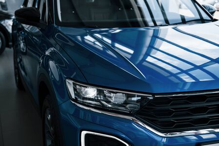 Front part of brand new modern blue car. Parked at showroom. Reflection in the headlights.の写真素材