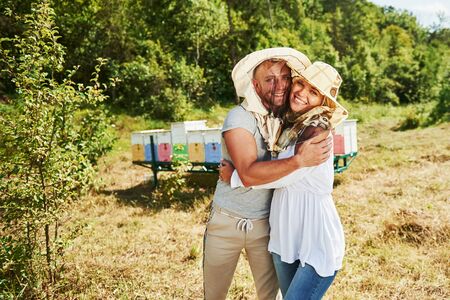 Portrait of two lovely beekeepers. Stands together near the hives. Sweet couple embracing.の写真素材
