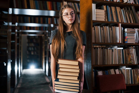 There is a lot of information in that books that in hands. Female student is in library. Conception...