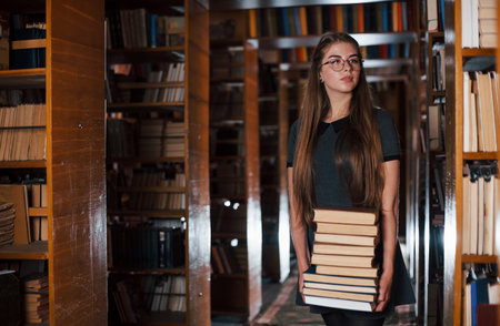 There is a lot of information in that books that in hands. Female student is in library. Conception...