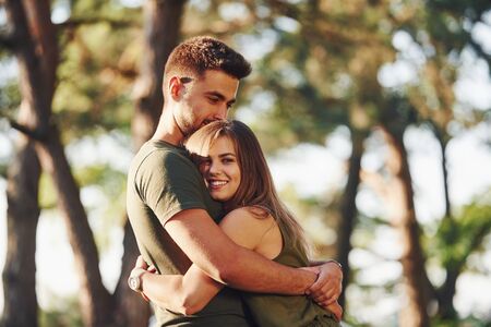 Happy together. Embracing each other. Beautiful young couple have a good time in the forest at daytime.の写真素材
