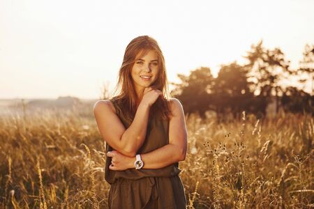 Portrait of happy girl that standing in the field illuminated by sunlight.の写真素材