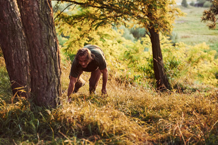Tired traveler on the hill. Beautiful man in the forest. Good weather. Beautiful orange colored sunlight.の写真素材