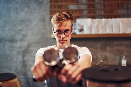Focused photo. Young male cafe worker indoors. Conception of business and service.の写真素材