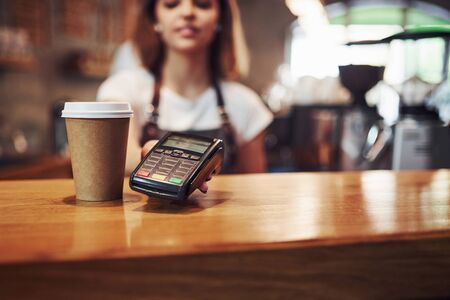 Device for paying. Young female cafe worker indoors. Conception of business and service.の写真素材