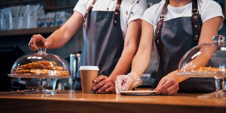 Two young cafe workers indoors. Conception of business and service.の写真素材
