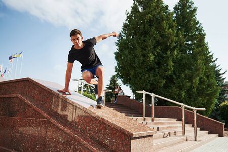 Above the obstacle. Young sports man doing parkour in the city at sunny daytime.の写真素材