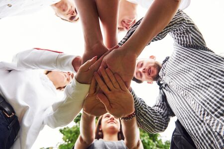 Close up view of hands of the young team of successful friends outdoors.の写真素材