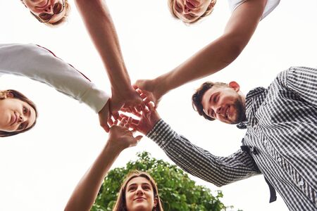 Close up view of hands of the young team of successful friends outdoors.の写真素材