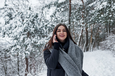 Cherful brunette have conversation while have a walk in winter forest.