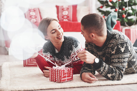 Hope its what I think. Lovely young couple lying on the floor of living room at new year time with...